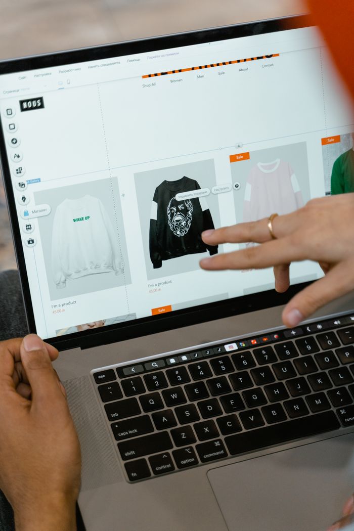 Close-up view of hands using a laptop indoors to browse a shopping website.
