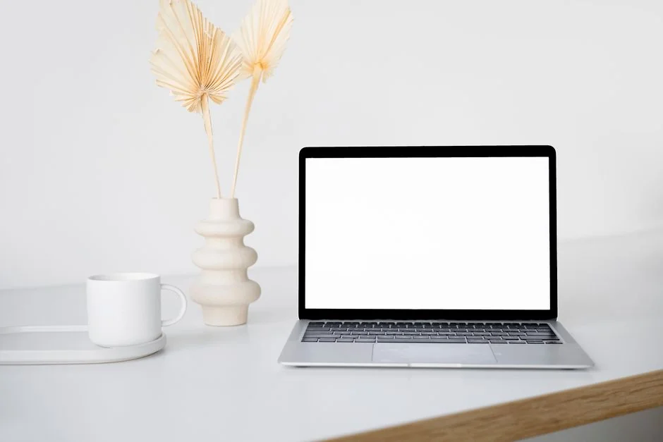 A laptop on a bed showing web design software, creating a cozy workspace.